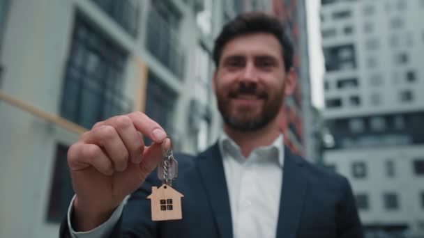 agent nieruchomości biznesmen kaukaski brodaty mężczyzna nabywca najemca mężczyzna trzymać klucze od nowego domu budynek wynajem mieszkania mieszkanie zmiana domu przeniesienie komercyjne umowa najmu mieszkania w mieście - Materiał filmowy, wideo