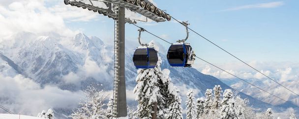 Νέα μοντέρνα ευρύχωρη μεγάλη καμπίνα σκι ανελκυστήρα γόνδολα κατά χιονισμένο δέντρο δάσος και βουνοκορφές που καλύπτονται από χιόνι τοπίο σε πολυτελές χειμερινό αλπικό θέρετρο. Χειμερινά σπορ αναψυχής, αναψυχή και ταξίδια. - Φωτογραφία, εικόνα