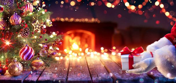 Papai Noel Dê Presente Sob Árvore de Natal Caixa de presente e ornamento Em Casa Interior Com Abstrato Desfocado Luzes À Noite - Foto, Imagem