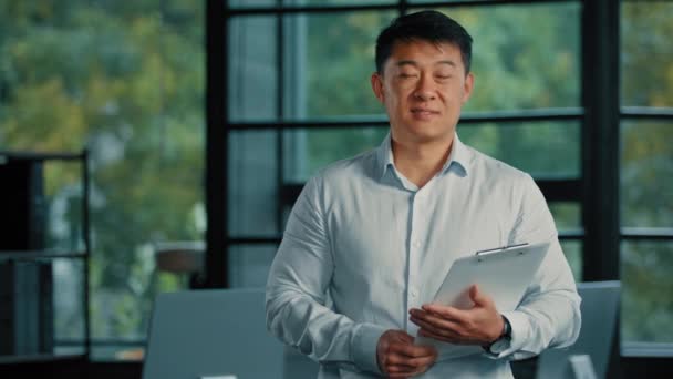 Aziatisch business agent bankier ceo manager werknemer man 40s zakenman koreaans chinees volwassene middelbare leeftijd man bezit financiële documenten verzekering stand in modern kantoor bedrijf succesvol beroep - Video