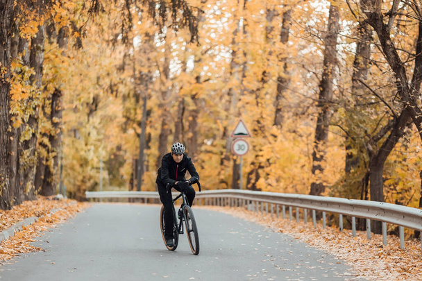 Junger hübscher, athletischer Mann steht mit Fahrrad im Herbstpark. - Foto, Bild