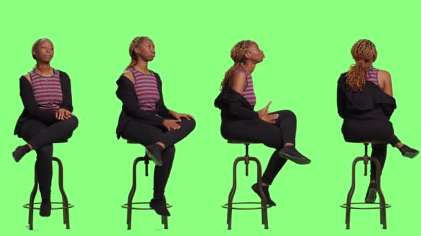 積極的な笑顔の女の子の椅子にフルボディの緑の背景の上に4つの側面に座って、ラインで待っていると準備。リラックスした女性は緑の画面の背景の上に準備に座っている. - 映像、動画