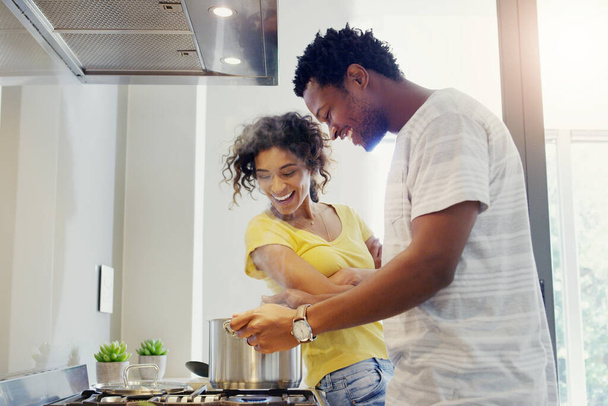 Its getting hot in here. a young couple cooking together in the kitchen at home - Foto, Bild