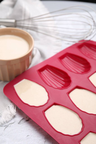Baking mold for madeleine cookies with batter on white table, closeup - Photo, image