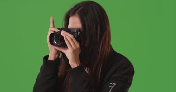 Aantrekkelijke fotograaf student neemt foto 's en focust digitale camera lens op greenscreen. Close-up van creatieve fotograaf met behulp van dslr camera om foto 's te maken op groen scherm. 4k - Video