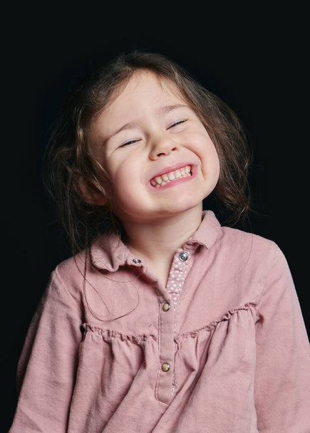 cute girl making expressive faces in the studio against a black background - Foto, Imagen