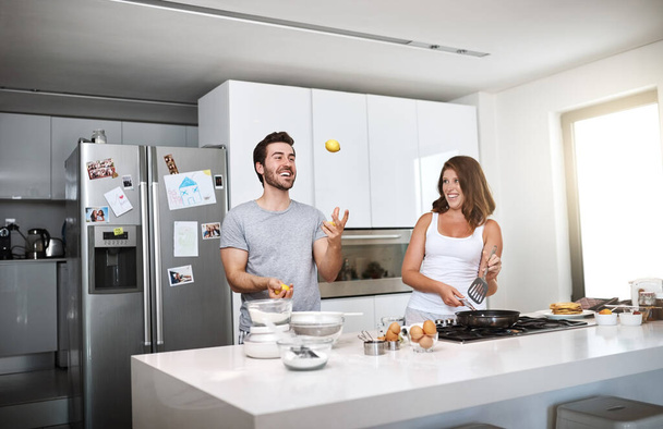 Play time is happy time. a happy young couple preparing breakfast in the morning - Foto, afbeelding