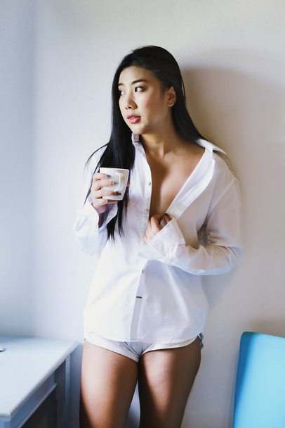 Улыбающаяся спокойная молодая женщина пьет кофе дома - Фото, изображение