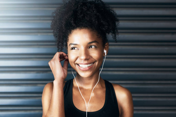 Nem élhetsz pozitívan, ha negatívan gondolkodsz. egy sportos fiatal nő zenét hallgat, miközben szürke háttérrel gyakorol - Fotó, kép