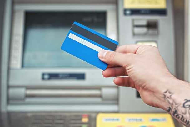 Main tenant une carte en plastique près du distributeur automatique. Paiement par carte bancaire
. - Photo, image