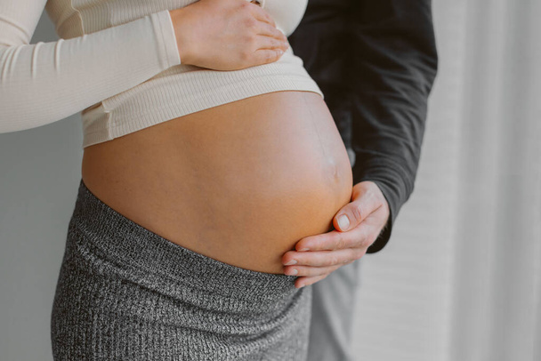 Couple expecting child baby bump man caressing pregnant woman stomach during pregnancy. Maternity shoot. - Fotó, kép