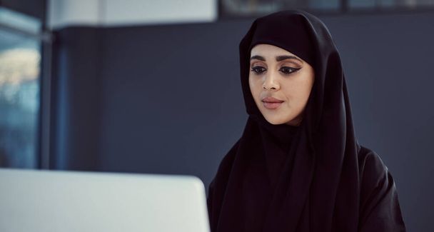 Trabajar duro y el éxito seguirá. una atractiva joven mujer de negocios árabe trabajando en su portátil en la oficina - Foto, imagen