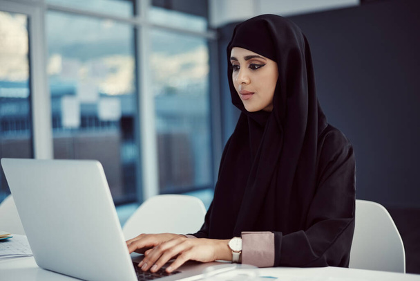 Wireless technology helps get the job done. an attractive young arabic businesswoman working on her laptop in the office - Fotografie, Obrázek
