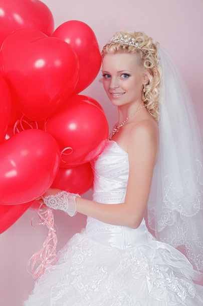 Blonde vrouw met rode ballonnen in hartvormige glimlachen - Foto, afbeelding