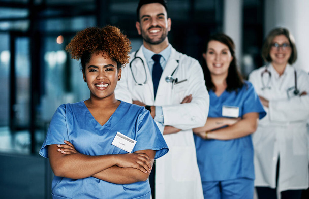 Мы здесь ради твоего здоровья. Портрет команды уверенных в себе врачей, стоящих вместе в больнице - Фото, изображение