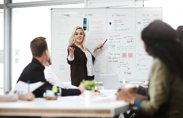 Working towards getting the results they seek. a businesswoman giving a presentation to her colleagues on a whiteboard in a boardroom - Foto, afbeelding