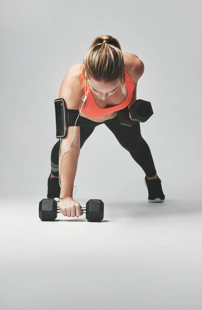 Vahvempi kuin eilen. Studio kuva urheilullinen nuori nainen treenata käsipainot harmaata taustaa vasten - Valokuva, kuva