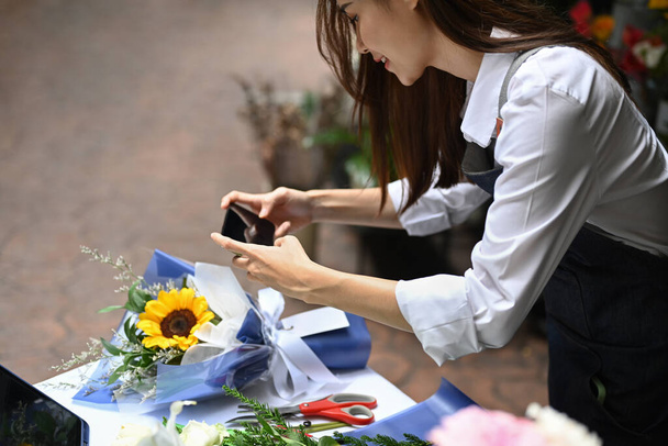 Zdjęcie kwiaciarni kobiet tworząc piękny bukiet kolorowych różnych kwiatów w jej kwiaciarni. Koncepcja działalności gospodarczej, sprzedaży i kwiaciarni. - Zdjęcie, obraz