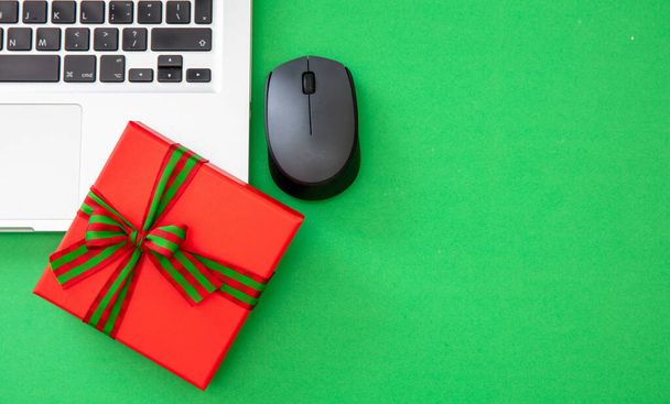 Cyber Monday Sale. Rote Geschenkschachtel mit Schleife und Computer-Laptop auf grünem Hintergrund, Kopierraum, Ansicht von oben - Foto, Bild