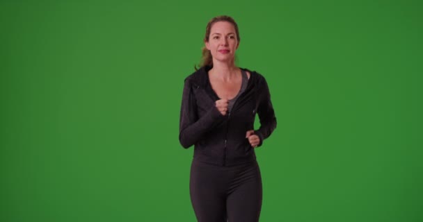 Femme d'âge moyen jogging lentement vers la caméra en tenue de sport sur écran vert. Sur écran vert à saisir ou à composer. - Séquence, vidéo