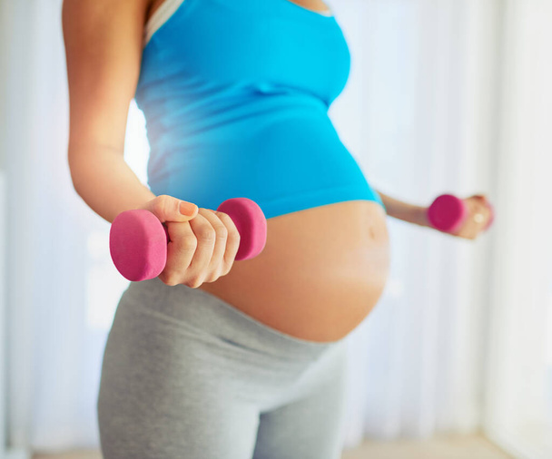 Strength training for mom to be. a pregnant woman working out with weights at home - Fotografie, Obrázek
