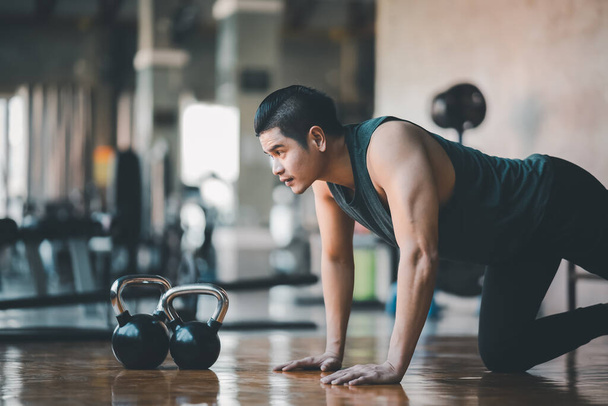 Asian fit sportsman doing push up exercise on the wood floor at the gym fitness. Sport man exercise at the sport center. Sport fitness gym concept. - Photo, Image