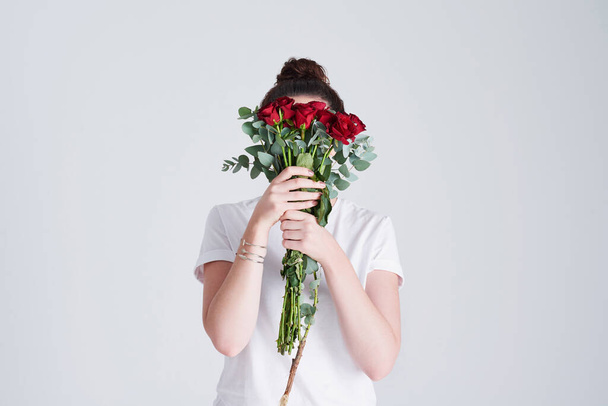 Květiny jsou nejpravdivější jazyk lásky. Studio záběr nerozpoznatelné ženy zakrývající její tvář s květinami na šedém pozadí - Fotografie, Obrázek