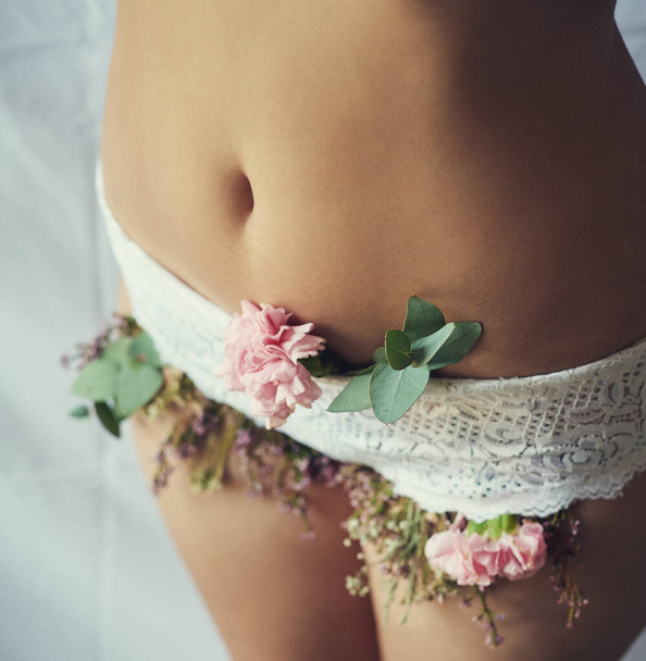 Blooming into womanhood. High angle shot of an unidentifiable young woman with flowers growing out of her lace panties - 写真・画像