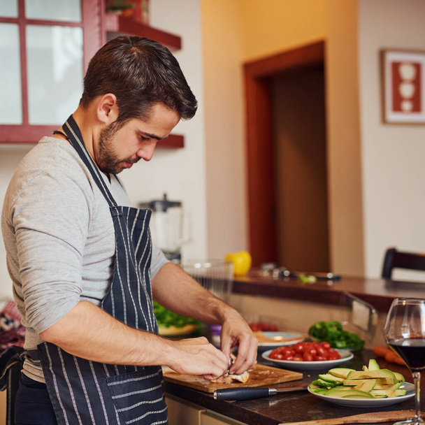 Udělej si z dobrého jídla palivo. šťastný mladý muž sekání zeleniny ve své kuchyni doma - Fotografie, Obrázek