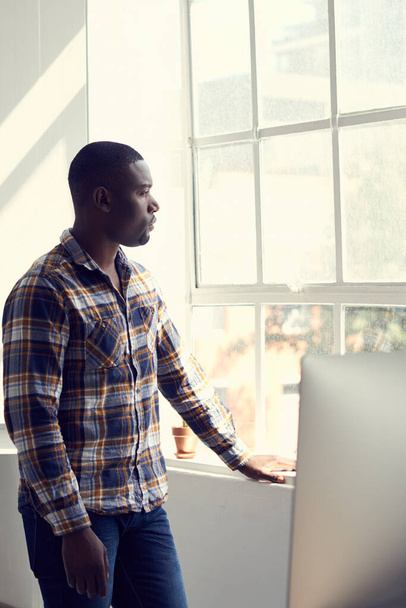 Предприниматели видят возможность во всем. молодой бизнесмен, задумчиво выглядывающий из окна современного офиса - Фото, изображение