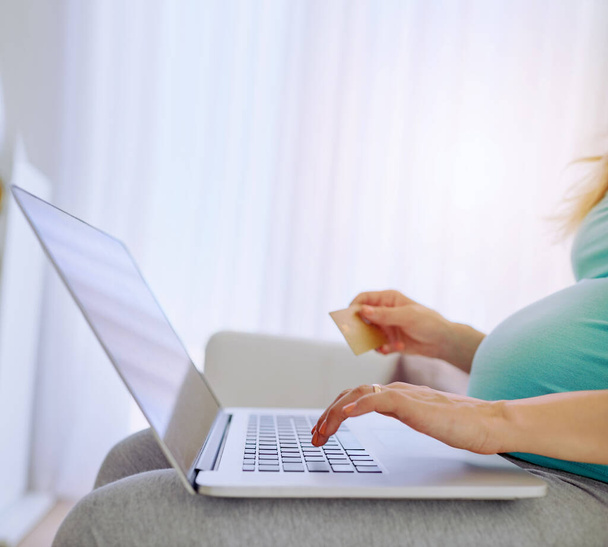 She just cant resist the cute baby clothes online. Closeup shot of a pregnant woman doing some online shopping at home - Photo, image