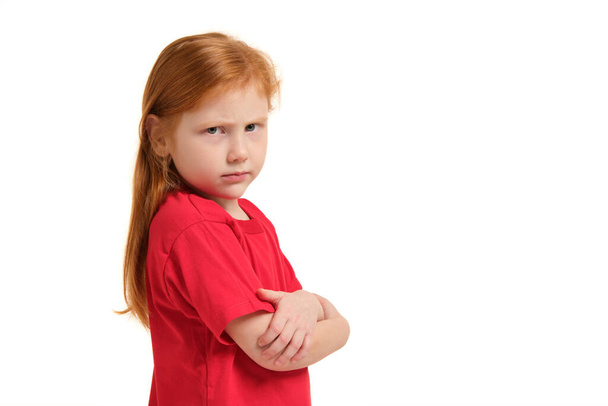 Linda niña con el pelo rojo y los brazos cruzados mirando enojado y molesto en la expresión de la cara frustrado e infeliz en la educación infantil y el concepto de emociones aislado fondo blanco. - Foto, imagen