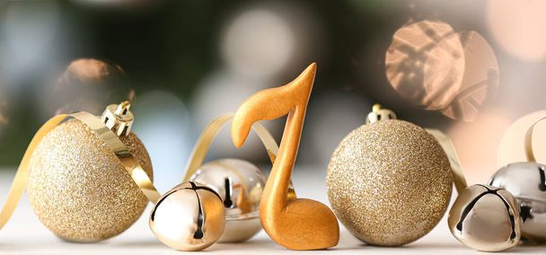 Signe de note, boules de Noël et cloches de jingle sur la table contre les lumières floues - Photo, image