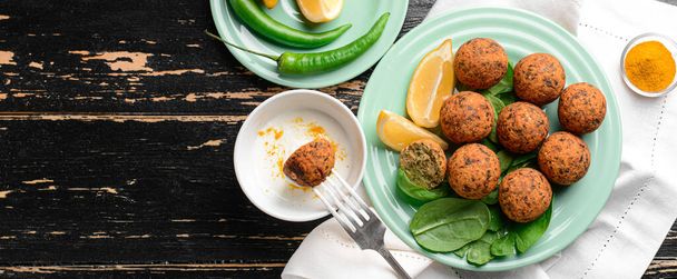 Plate with tasty falafel balls and sauce on dark wooden table - Photo, Image