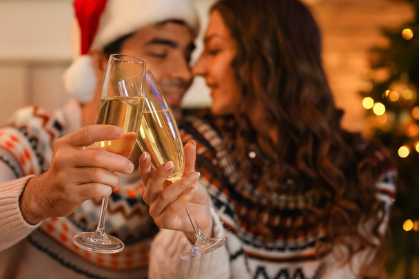 Young couple in love with glasses of champagne at home on Christmas eve, closeup - Фото, изображение