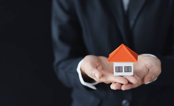 Agent nieruchomości posiadający model domu, podpisujący z klientem umowę kupna domu, ubezpieczenia lub kredytu. - Zdjęcie, obraz