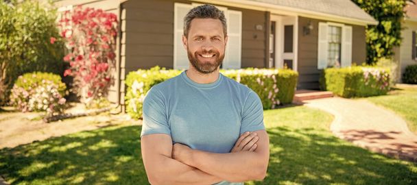 amazed unshaven guy crossed hands near house, realtor. Man face portrait, banner with copy space - Foto, afbeelding