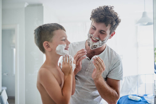 Un jour, tu auras aussi une vraie barbe. un père enseignant à son petit fils comment se raser dans la salle de bain à la maison - Photo, image