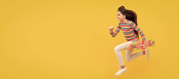 Run and jump. happy energetic child skateboarder jumping with penny board skateboard, childhood. Casual teen child horizontal poster. Banner header, copy space - 写真・画像
