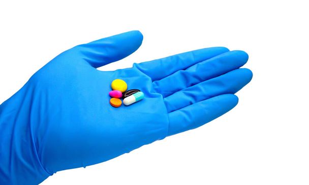 Tablety, více barev, lékařská ruka, v modrých lékařských rukavicích na bílém s výstřižkem. - Fotografie, Obrázek