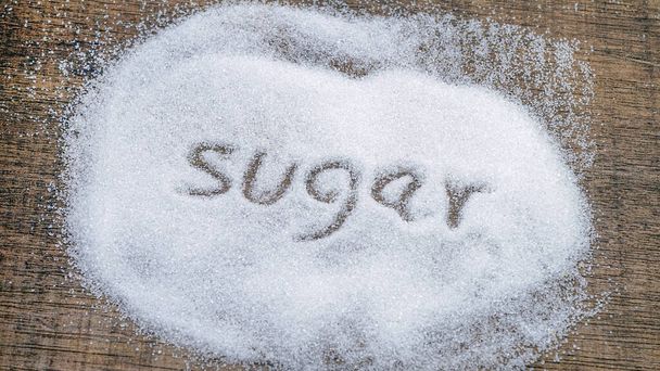 Açúcar de inscrição transformado em pilha de açúcar branco granulado
. - Foto, Imagem