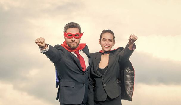 空を背景にスーパーヒーロースーツを着た笑顔のビジネスカップル. - 写真・画像