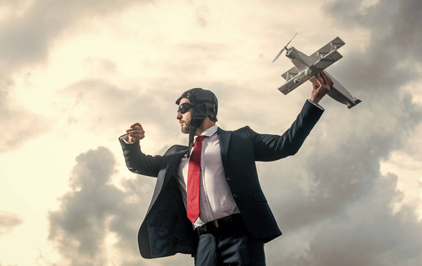 businessman check time on watch in suit and pilot hat launch plane toy. - Foto, Imagen