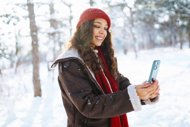 Smiling young woman taking selfie in winter forest. Winter holiday. - Valokuva, kuva