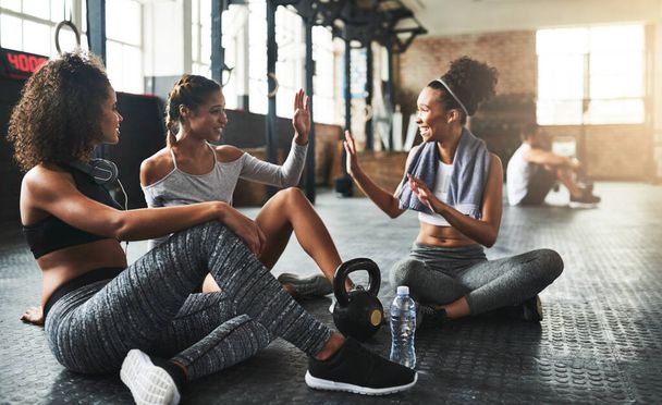 Wahre Freunde motivieren sich gegenseitig, sich fit zu halten. junge Frauen geben einander eine High Five, während sie im Fitnessstudio eine Pause einlegen - Foto, Bild