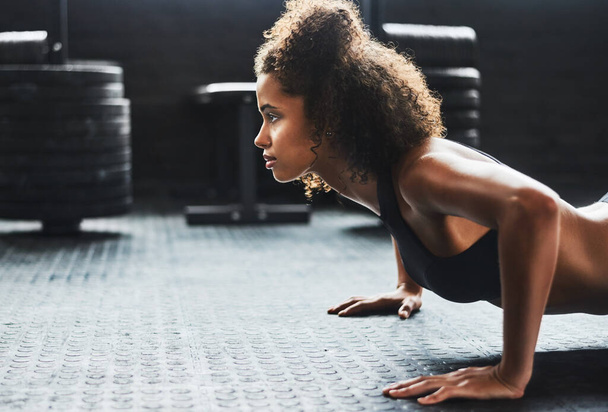 Mantente determinado y haz lo que sea mejor para ti. una joven haciendo flexiones en un gimnasio - Foto, imagen