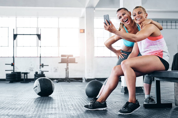 First gym buddies, now best friends. two young women taking a selfie at the gym - Foto, imagen