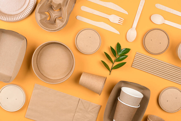 Milieuvriendelijke papieren gebruiksvoorwerpen - duurzame voedselverpakking op oranje achtergrond. Straat voedsel papier verpakking, recycleerbare papierwaren, nul afval verpakking concept. Platte lay stijl - Foto, afbeelding