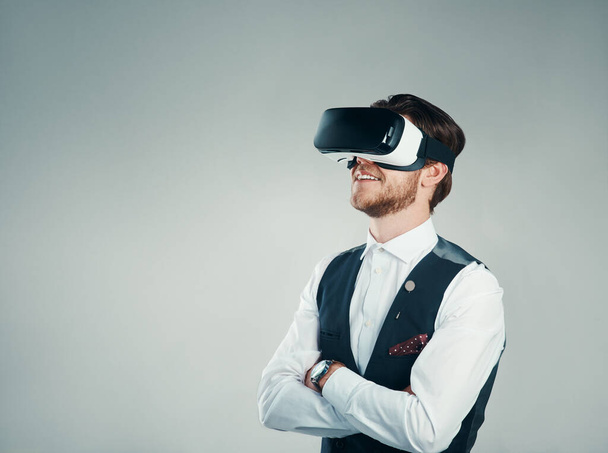 This is what modern business looks like. Studio shot of a handsome young businessman using a vr headset against a grey background - Photo, Image