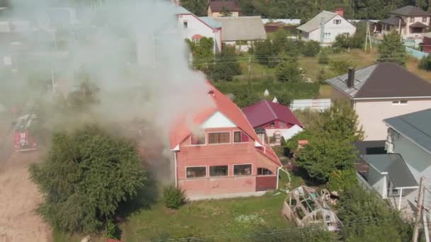Luchtdrone beelden van een brand in een rood privéhuis. Grijze rook. Hulpdiensten. Weg. Brandweerwagens. Hoge kwaliteit 4k beeldmateriaal - Video